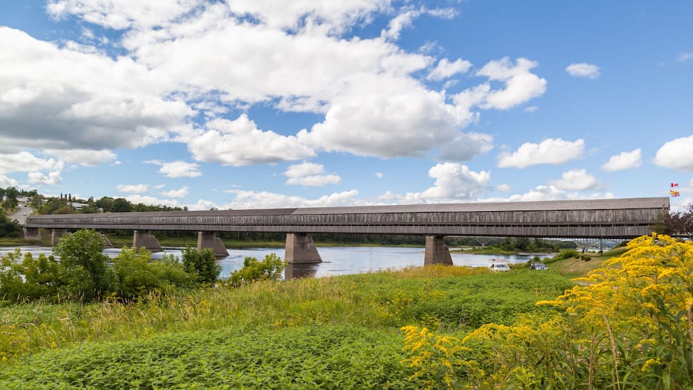 NEW BRUNSWICK, CANADA - August 6, 2017: Side view of Hartland covered bridge in New Brunswick. This 390-m (1,282-ft.) bridge opened on 1901, the longest wooden covered bridge in the world.