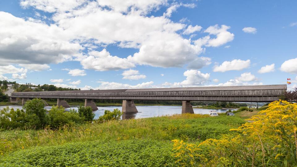 A wooden bridge over a river with a clear sky.