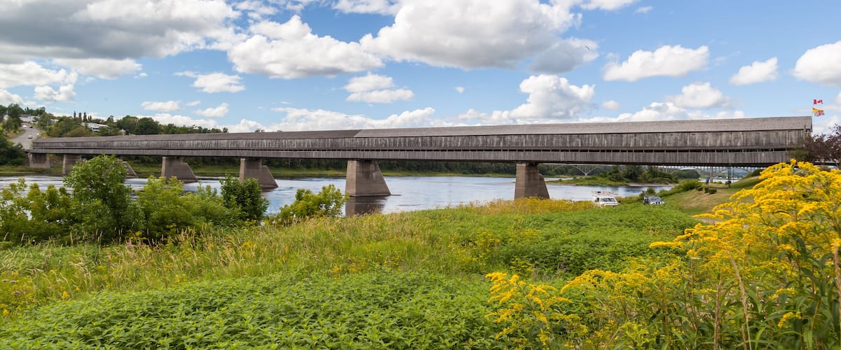 A wooden bridge over a river with a clear sky.