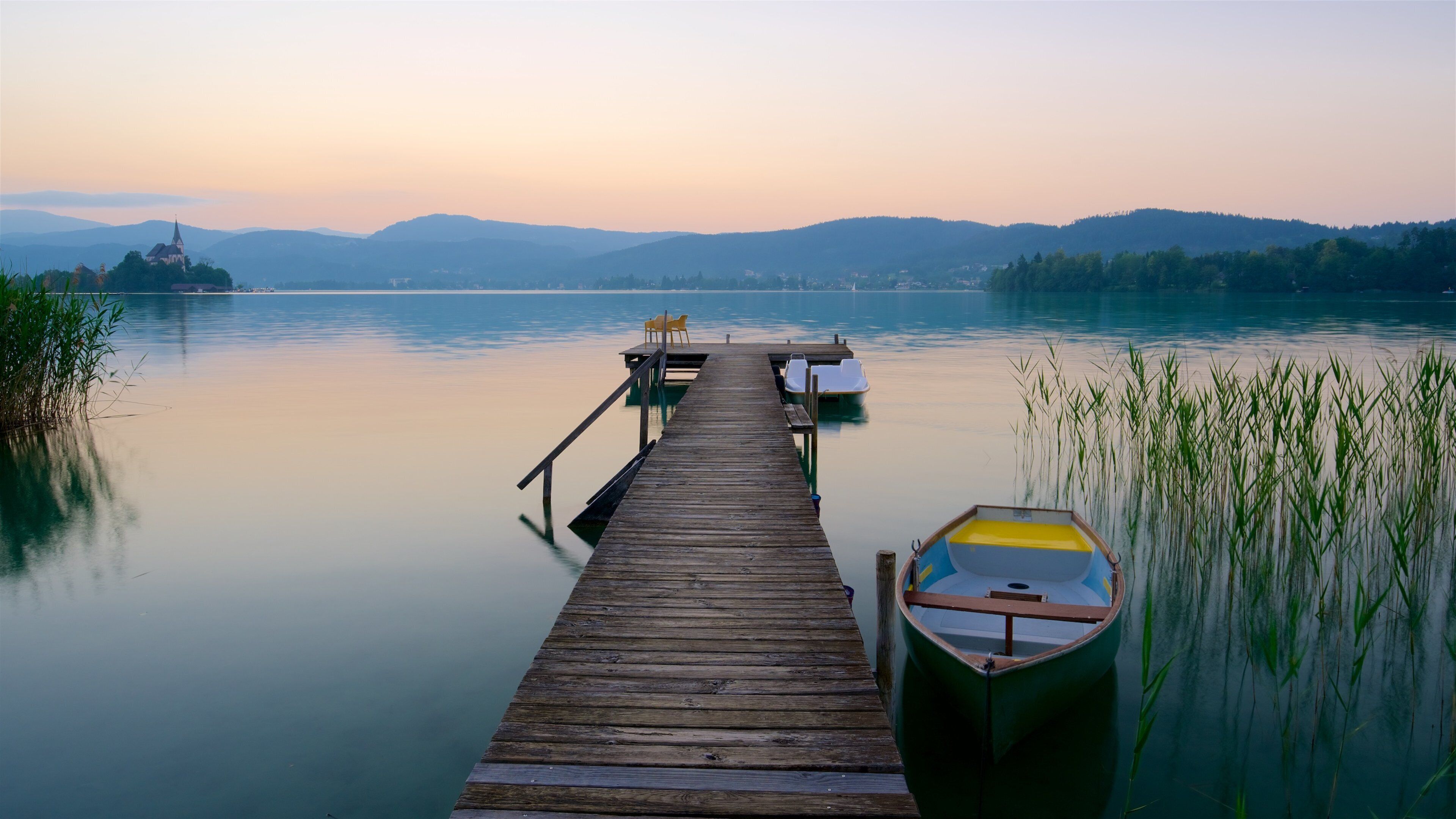 A wooden pier extending into calm waters, with a small boat docked at the end.
