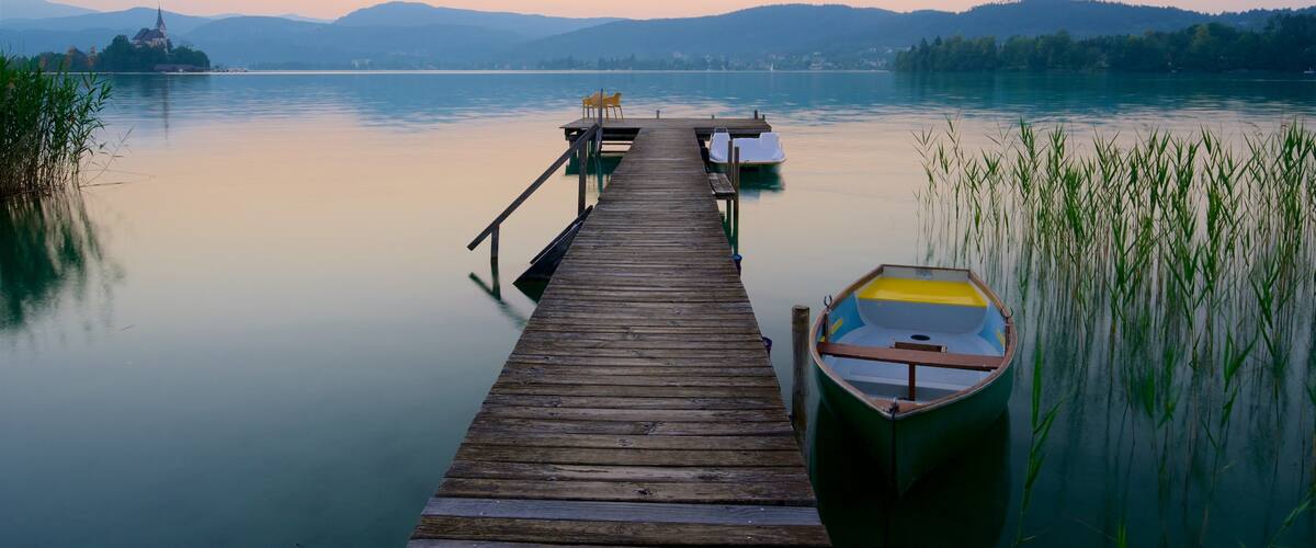 A wooden pier extending into calm waters, with a small boat docked at the end.
