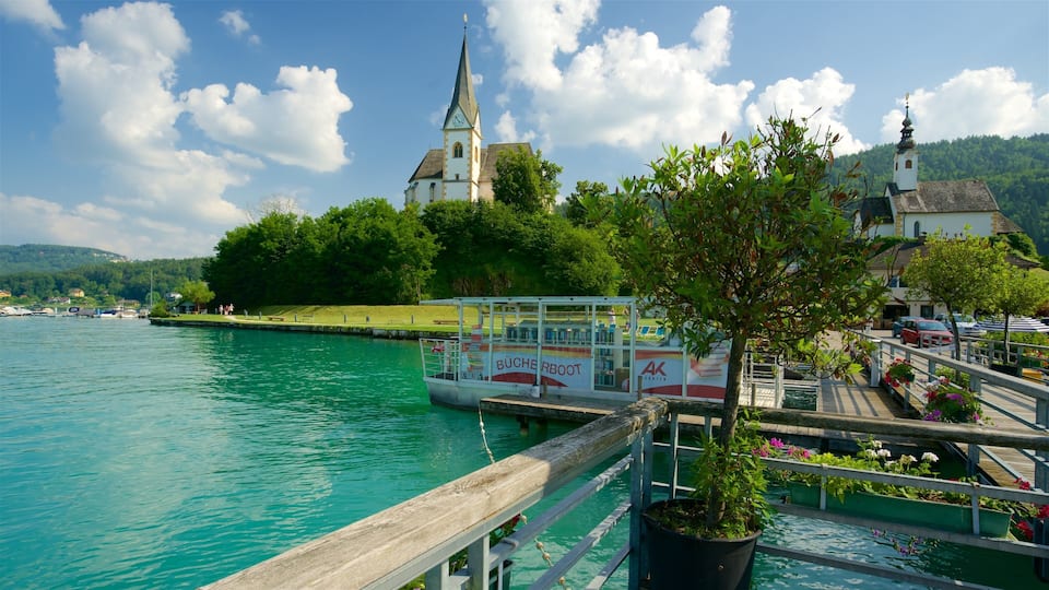 A boat docked at a pier with a church and lush greenery in the background.