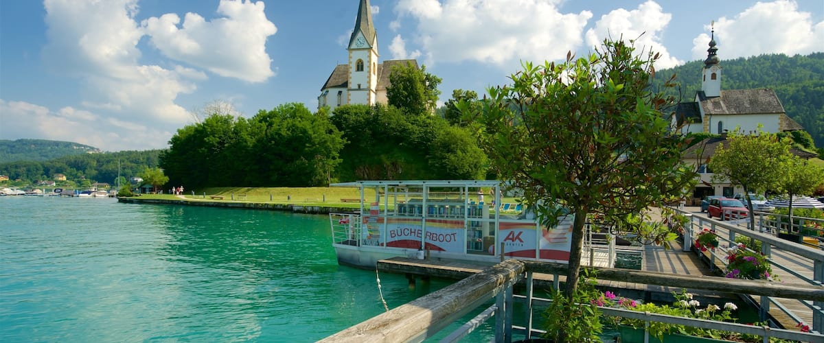 A boat docked at a pier with a church and lush greenery in the background.
