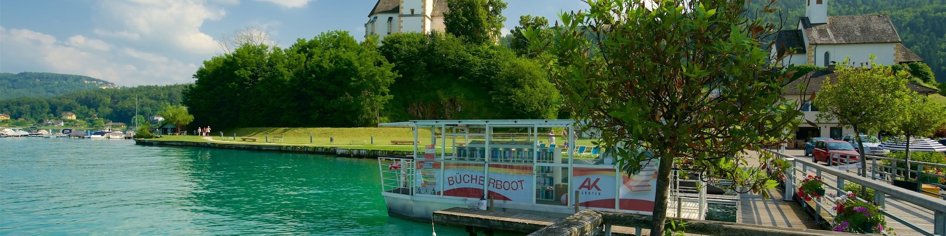 A boat docked at a pier with a church and lush greenery in the background.