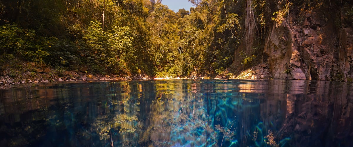 Un lac d’un bleu profond, entouré d’une forêt dense et de falaises rocheuses.