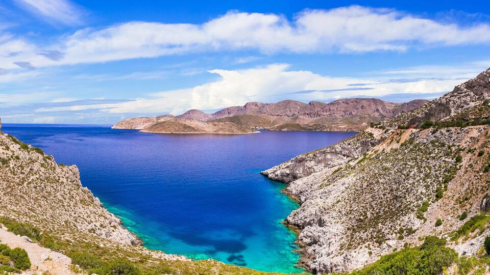 A coastal landscape with rugged cliffs and a clear blue sea.