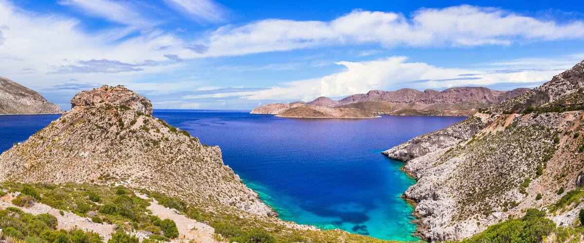 A coastal landscape with rugged cliffs and a clear blue sea.