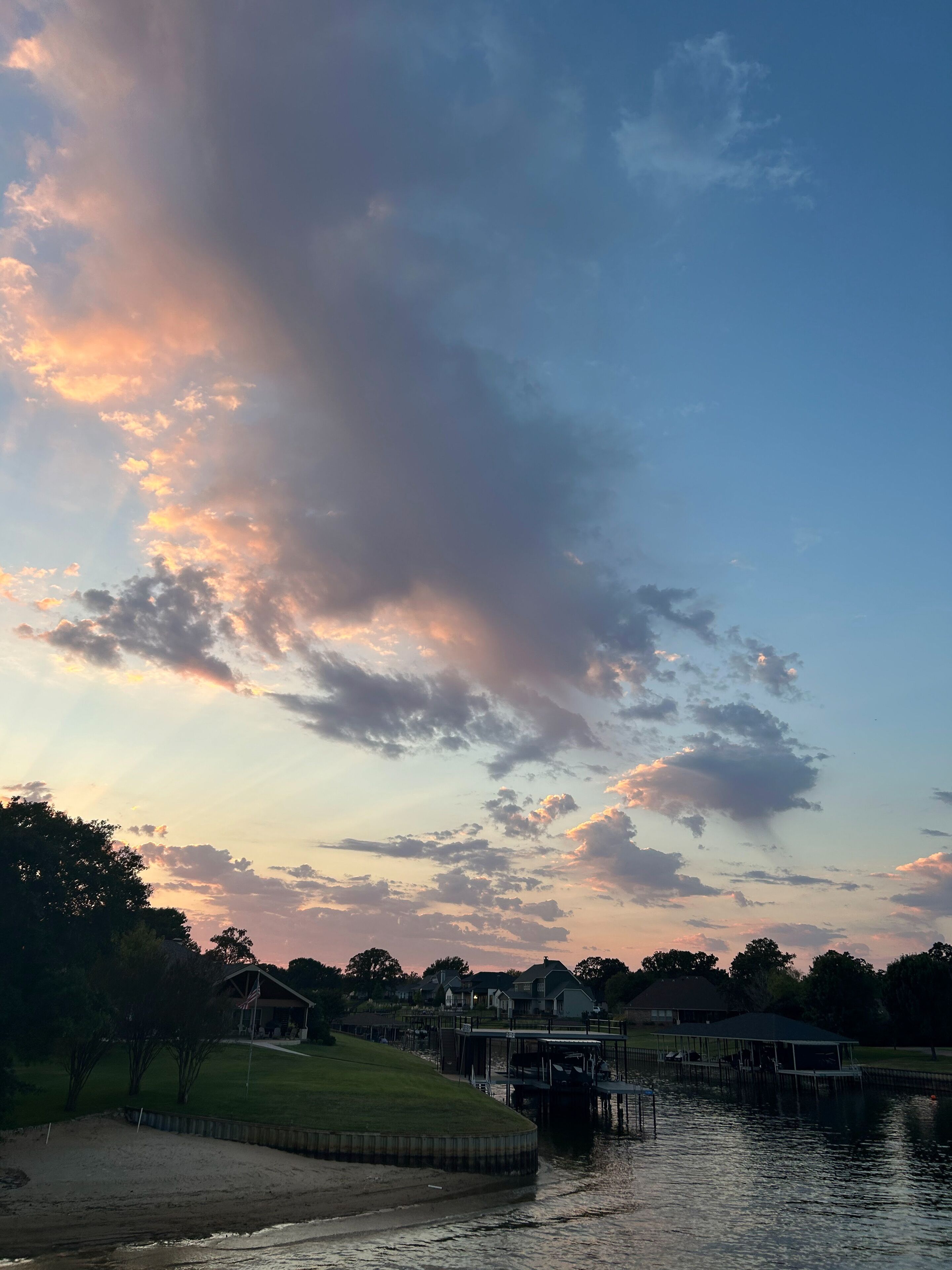 Colorful sunset clouds over Cedar Creek Reservoir waterfront in Texas