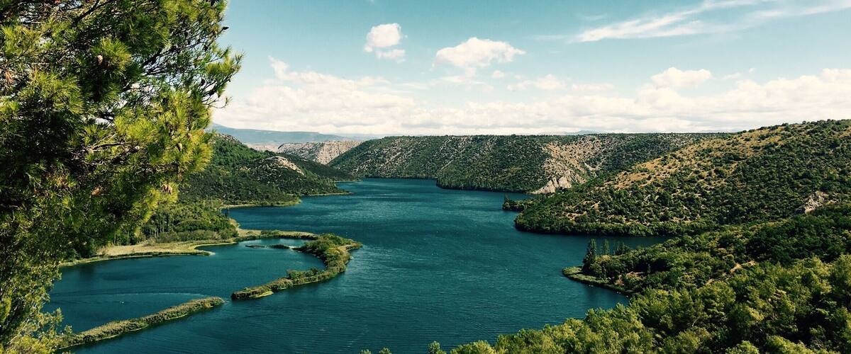 A river winding through a mountainous landscape with dense greenery and clear blue water.