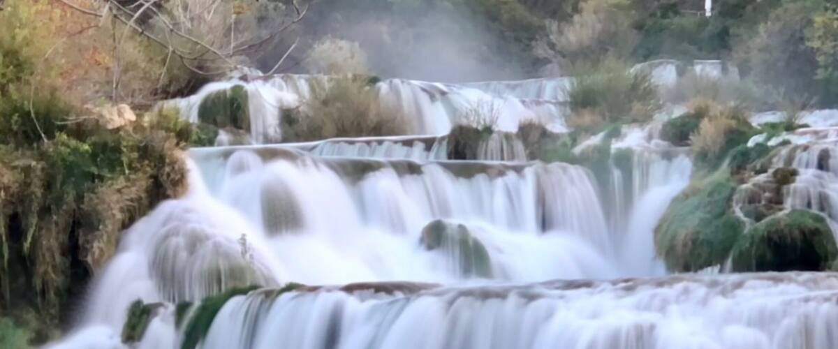 Een meerlaagse waterval omgeven door groen.