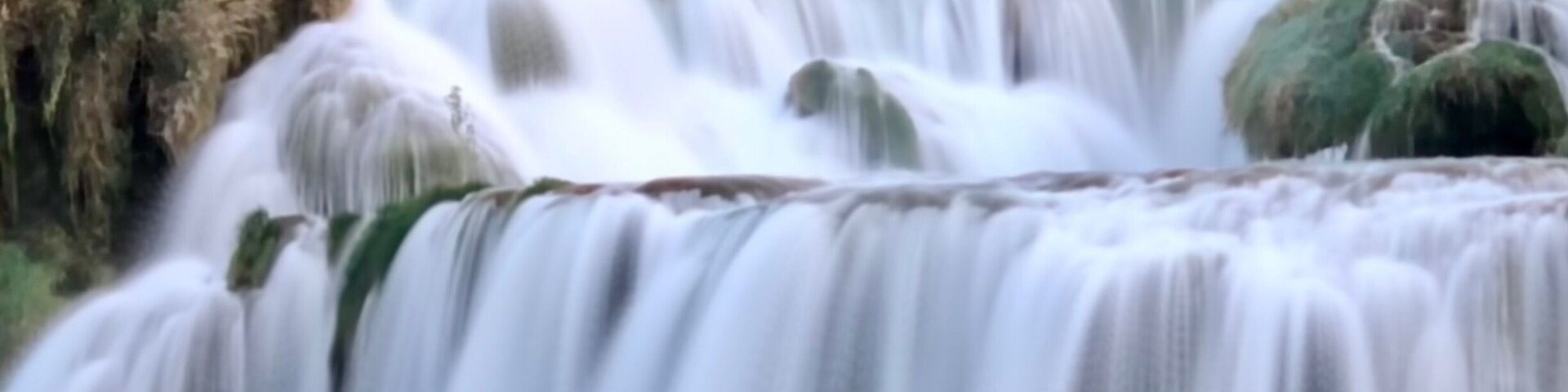 Una cascada escalonada rodeada de vegetación.