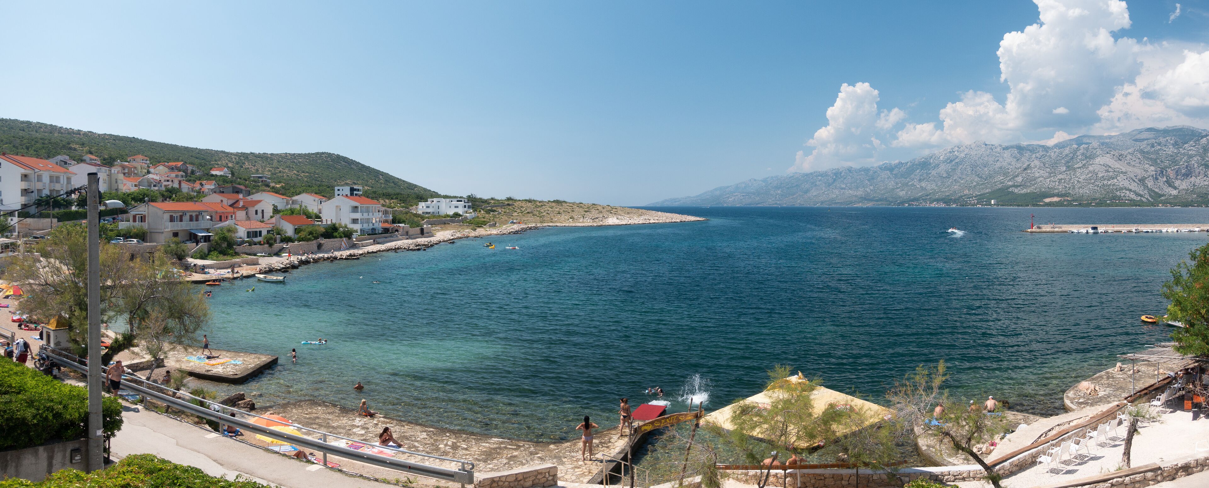 A coastal town with buildings, a pier, and clear blue sea.