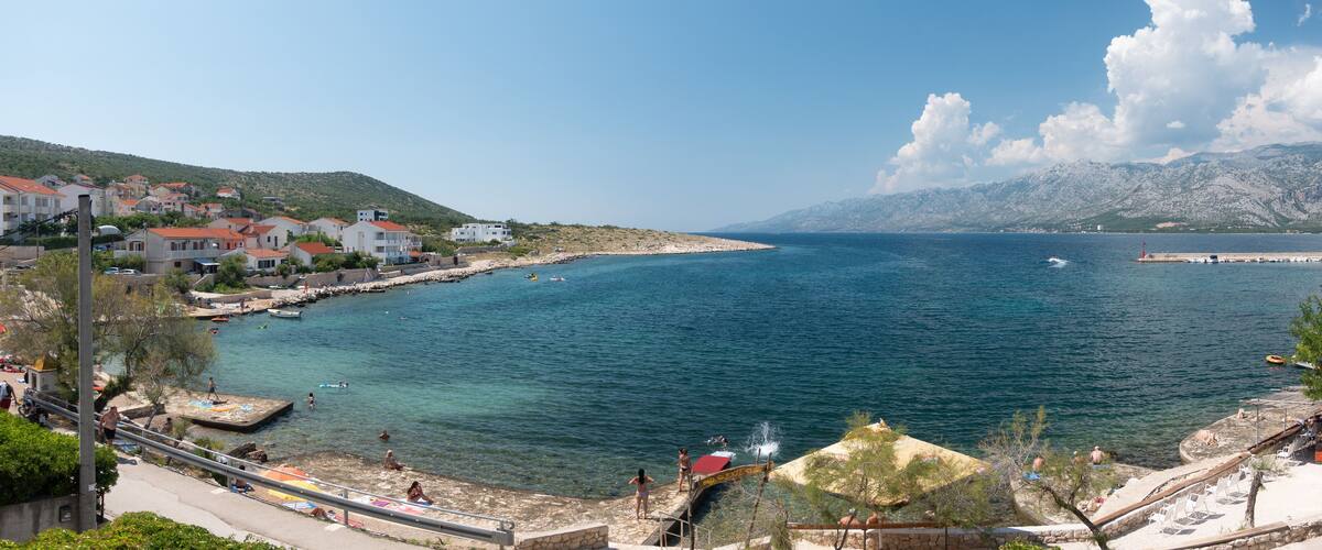 A coastal town with buildings, a pier, and clear blue sea.
