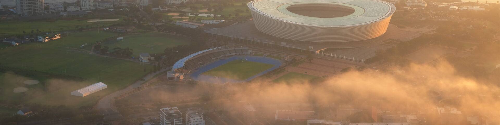 A stadium surrounded by residential buildings and a coastal area.