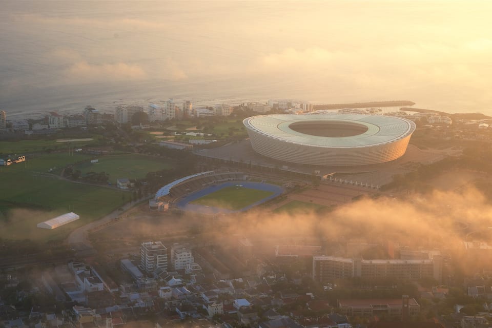 A stadium surrounded by residential buildings and a coastal area.