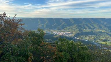 A mountainous landscape with a river, a bridge, and a town.