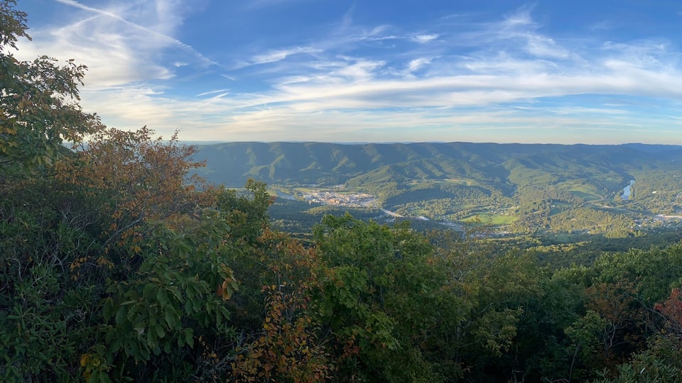 A mountainous landscape with dense forests and a valley below.