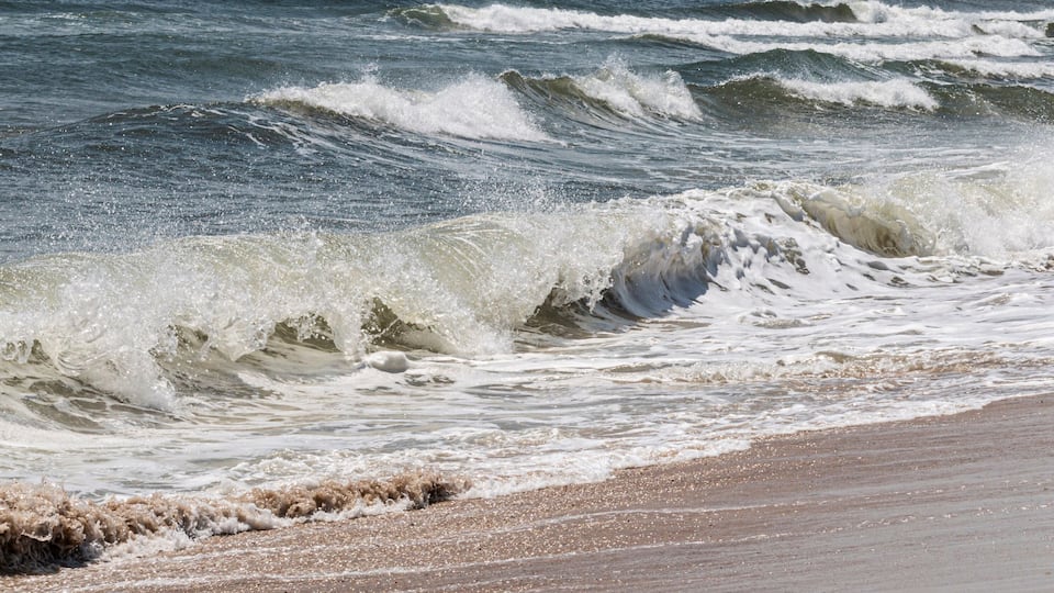 A beach with waves crashing onto the shore.