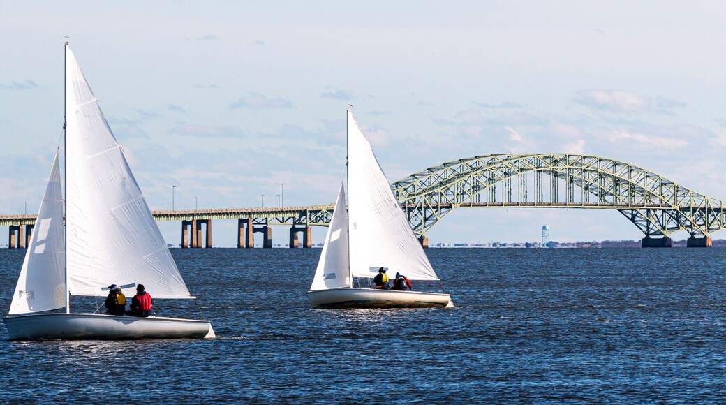 Two two person sailboats sailing toward West Islip with the Great South Bay bridge