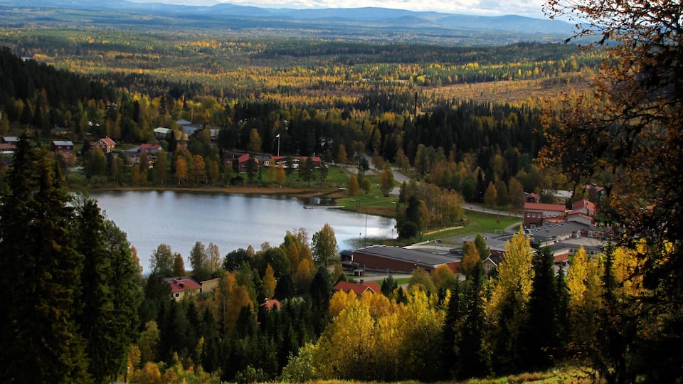 A lake surrounded by autumn-colored trees and houses.