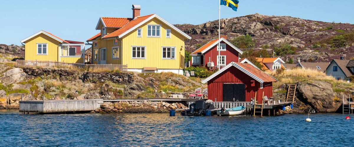 A coastal village with colorful houses, a dock, and a Swedish flag.