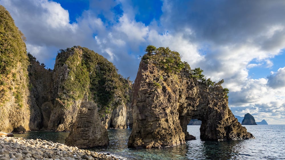 A coastal landscape with prominent rock formations and a clear sky.