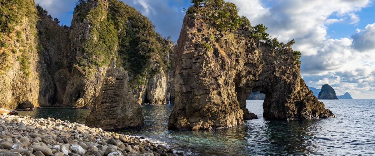 A coastal landscape with prominent rock formations and a clear sky.