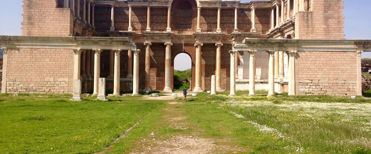 An ancient Roman amphitheater with columns and a central archway.