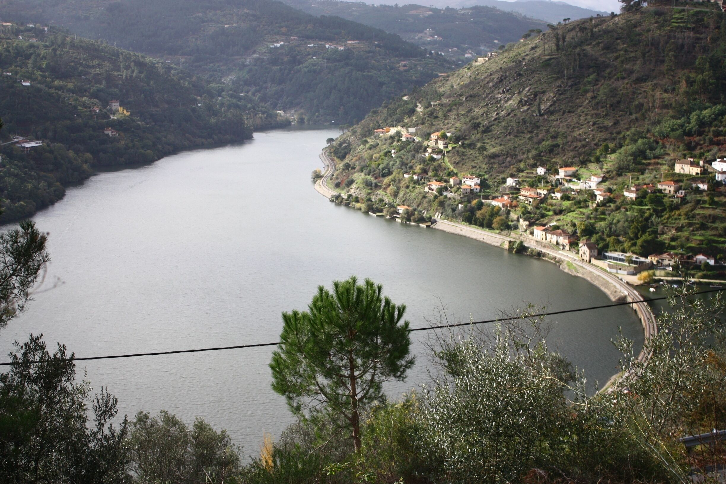 A river winding through a hilly landscape with scattered houses and trees.