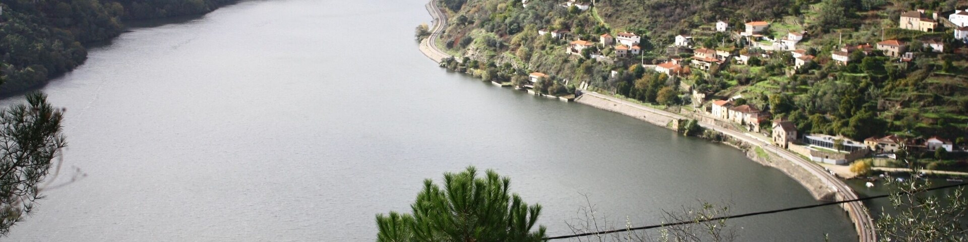 A river winding through a hilly landscape with scattered houses and trees.