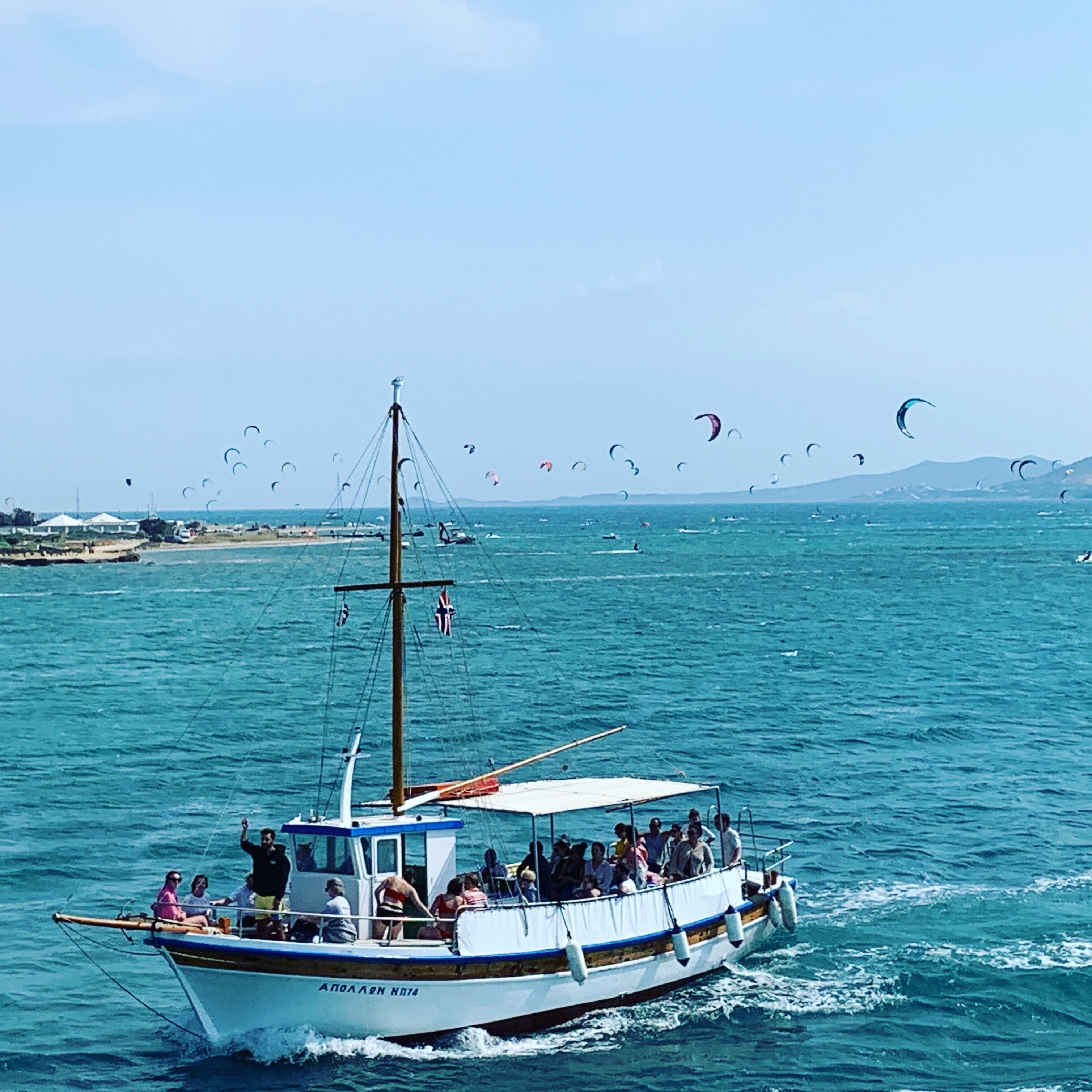 A boat with people on it and several kites in the background.