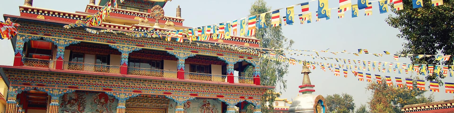 A multi-tiered temple with intricate murals and colorful flags.