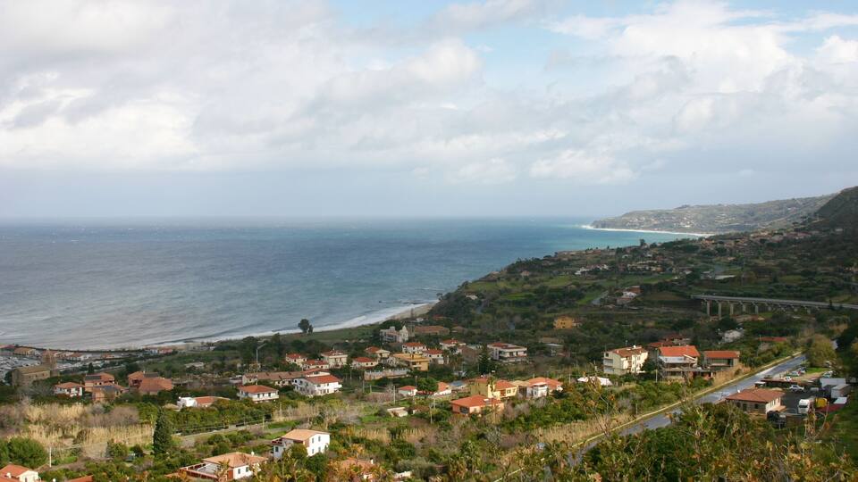 A coastal town with houses, a bridge, and the ocean.