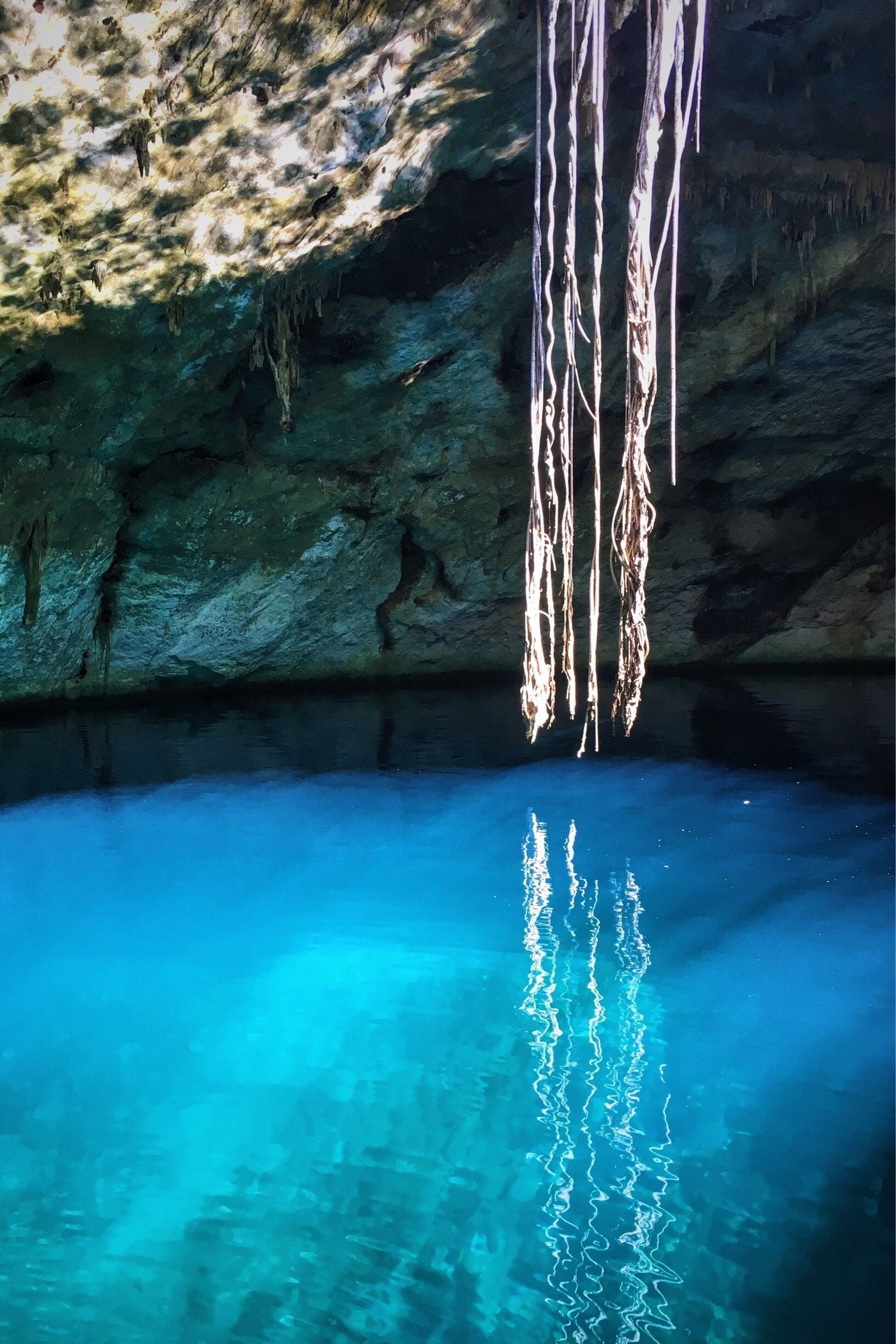 Una cueva con agua azul cristalina y estalactitas colgantes.
