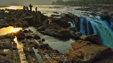 A waterfall cascading over rocks with people standing nearby.