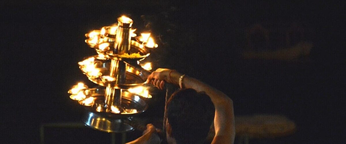 A person holding a traditional candle holder with multiple candles.