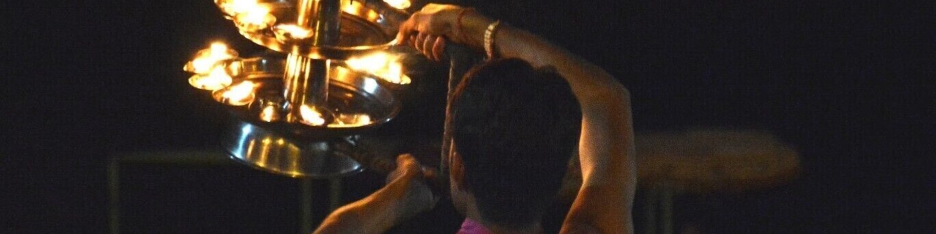 A person holding a traditional candle holder with multiple candles.
