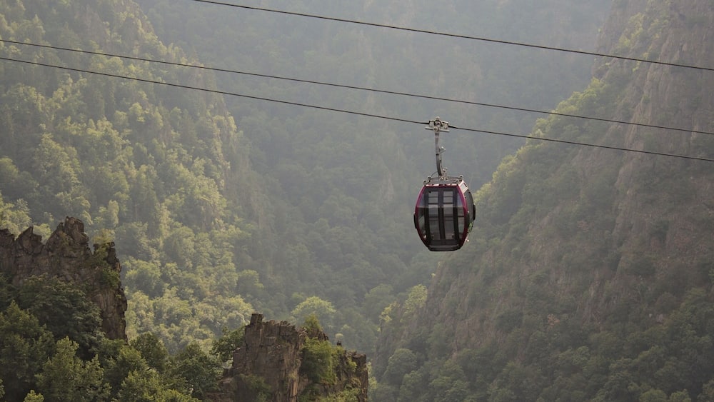 Eine Standseilbahn spannt sich über ein bewaldetes Tal mit steilen Felswänden.