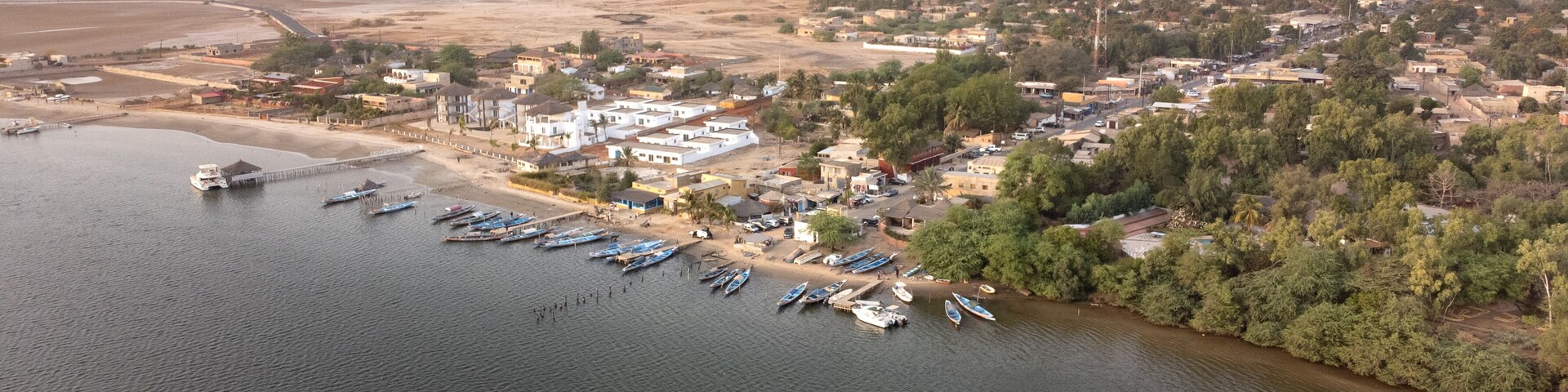 Vista aérea de un pueblo costero con un puerto deportivo, barcos y edificios.