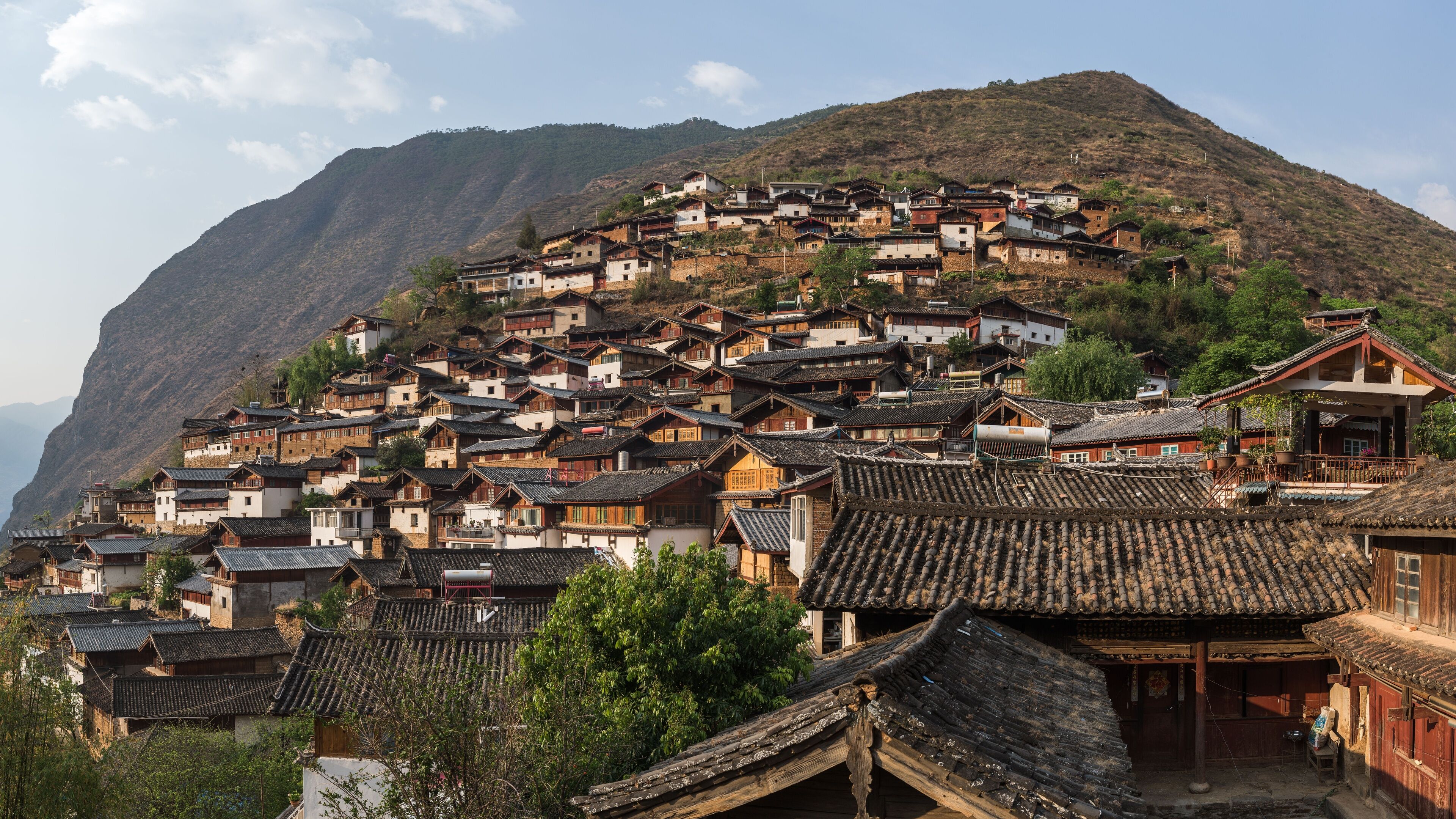 Traditional small houses of the Baoshan stone city in Lijiang China with mountains in the background