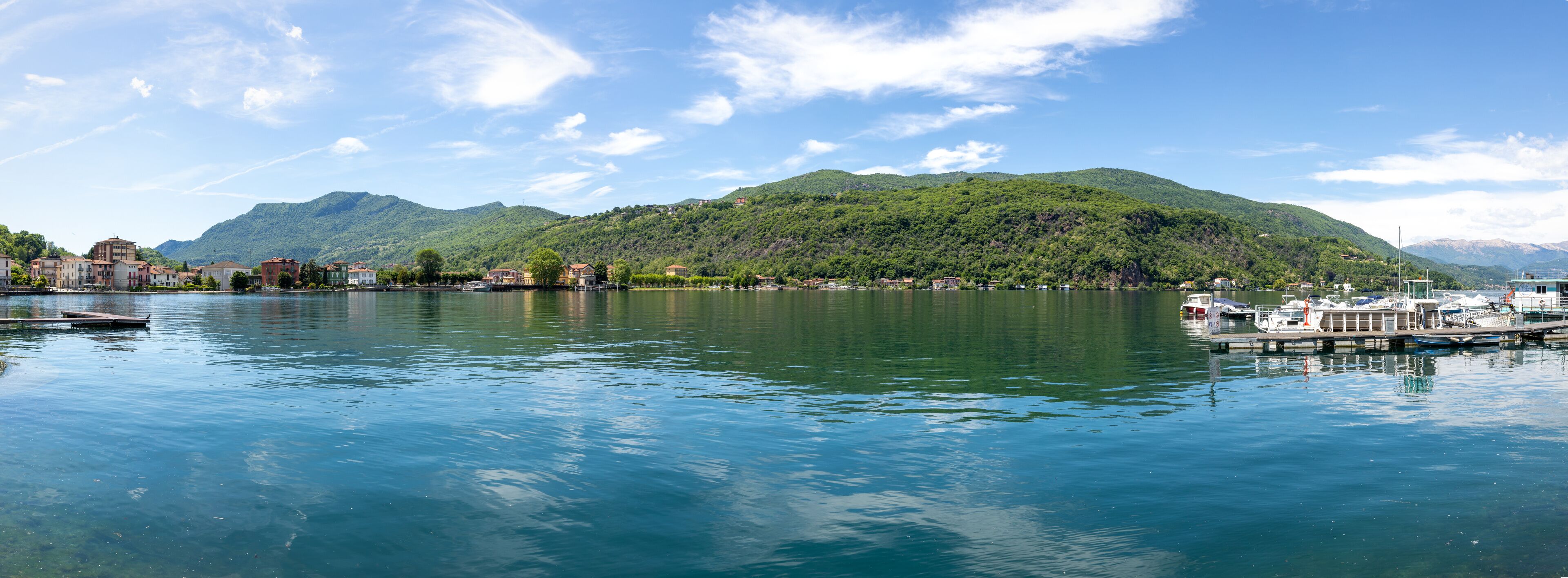 A calm lake with a dock, boats, and buildings along the shore.