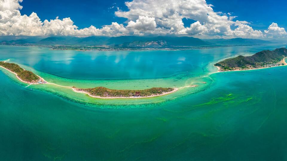 A tropical island with clear turquoise waters, a white sandy beach, and lush greenery.