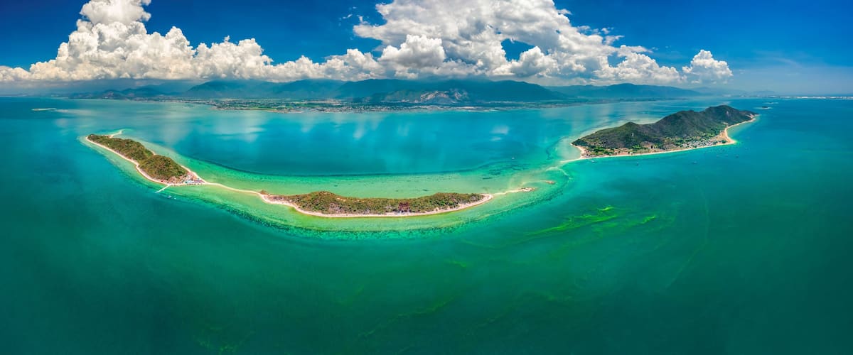 A tropical island with clear turquoise waters, a white sandy beach, and lush greenery.