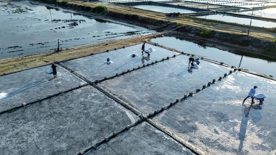 A large, flat, industrial area with multiple rectangular sections, some with water and others with dry land.