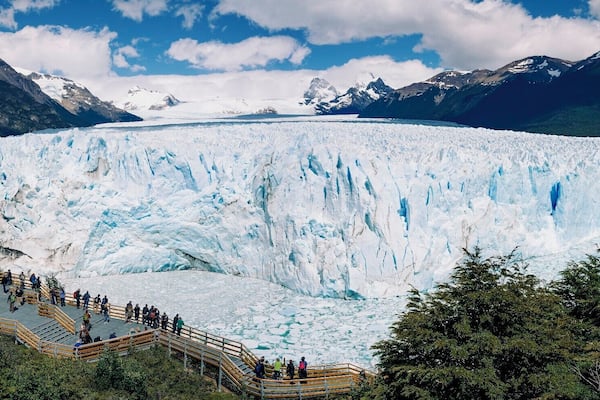 Un vaste glacier doté d’une plateforme d’observation, avec des personnes se trouvant aux alentours.
