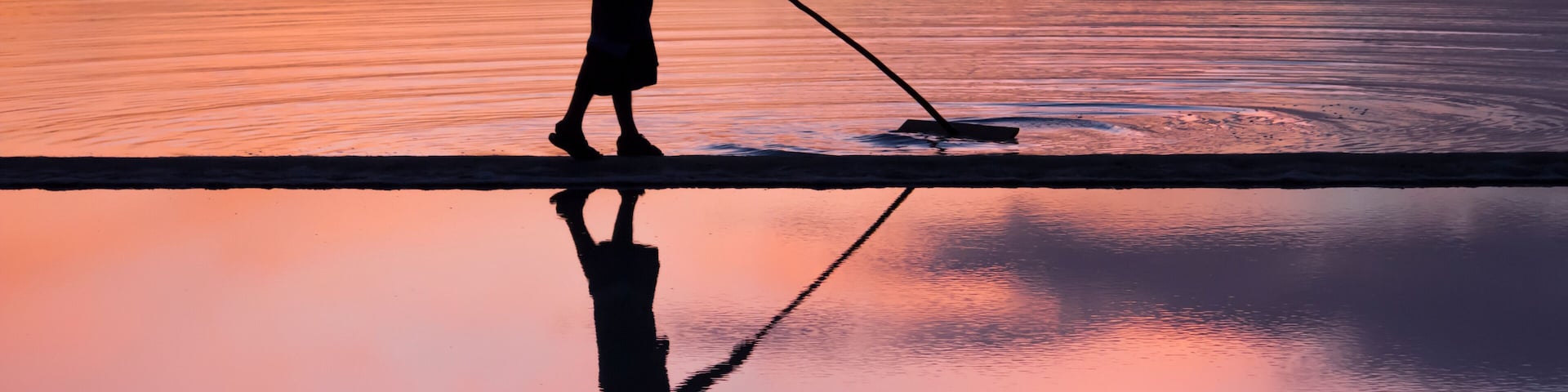 Una persona caminando sobre una superficie reflectante con un perro, generando un reflejo simétrico.