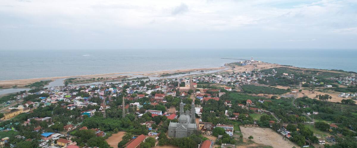 A coastal town with a prominent church, a beach, and a lighthouse.