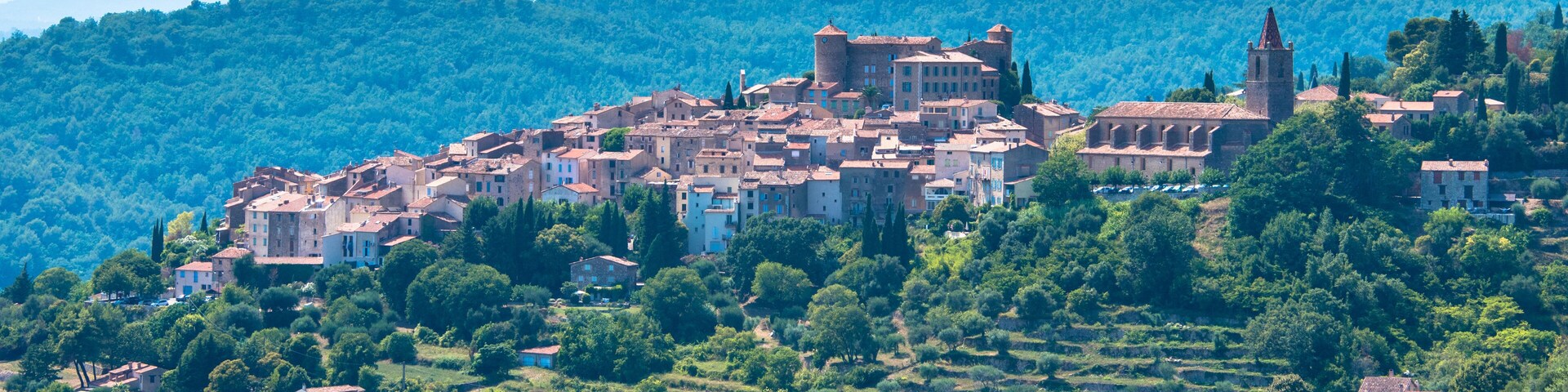 A historic town nestled in a valley with terraced fields, surrounded by lush green hills and mountains.