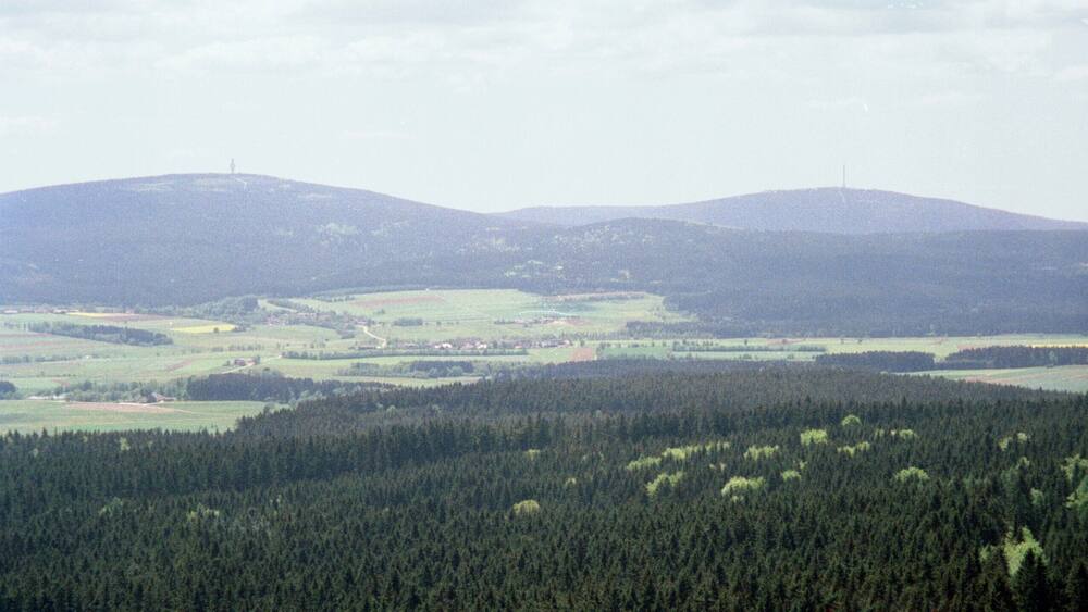 Un paysage montagneux, avec de vastes forêts et de vastes champs à perte de vue.