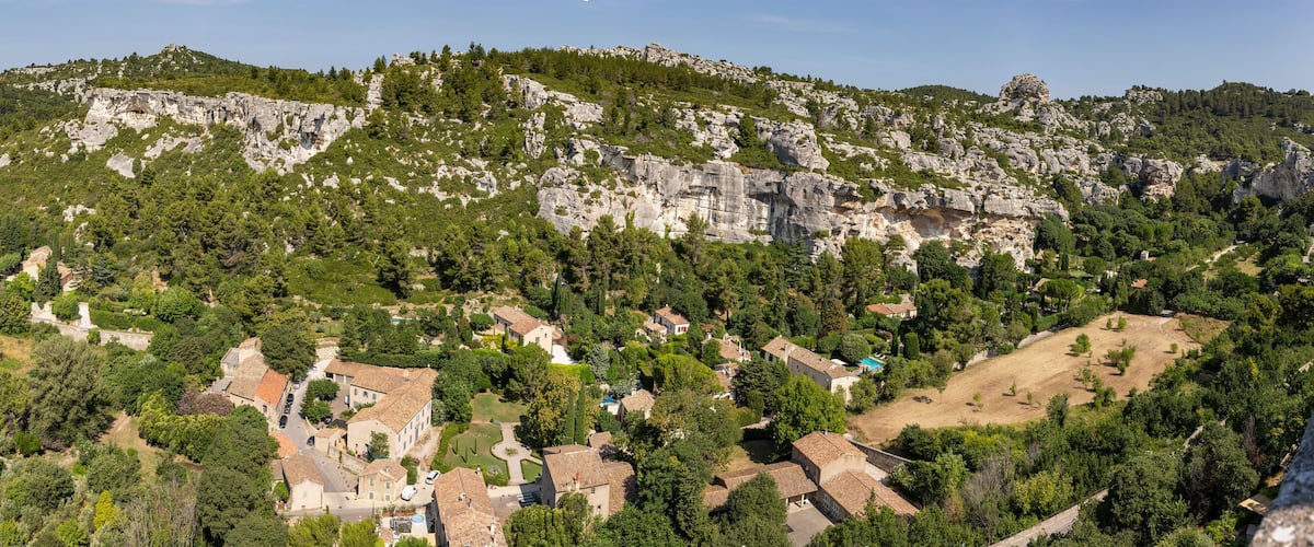 A mountainous landscape with a village nestled among rocky cliffs and dense forests.